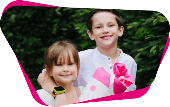 Ein Junge und ein Mädchen lächeln in die Kamera, der Junge trägt eine Kinder-Smartwatch, das Mädchen hält eine pink-weiße Schultüte.